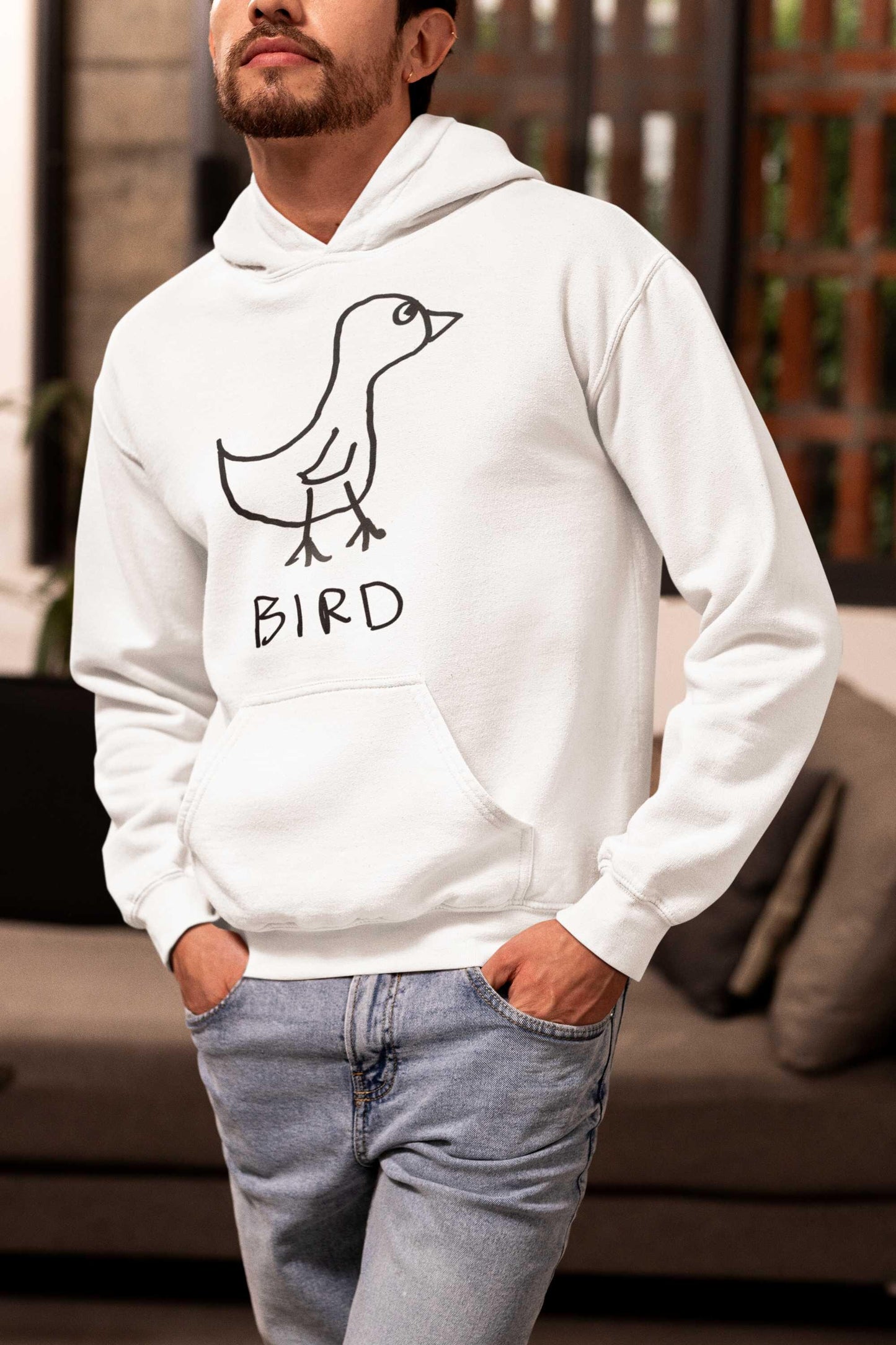 young man wearing jean and a white hooded pullover sweatshirt featuring a crude marker drawing of a bird with the word "Bird" underneath