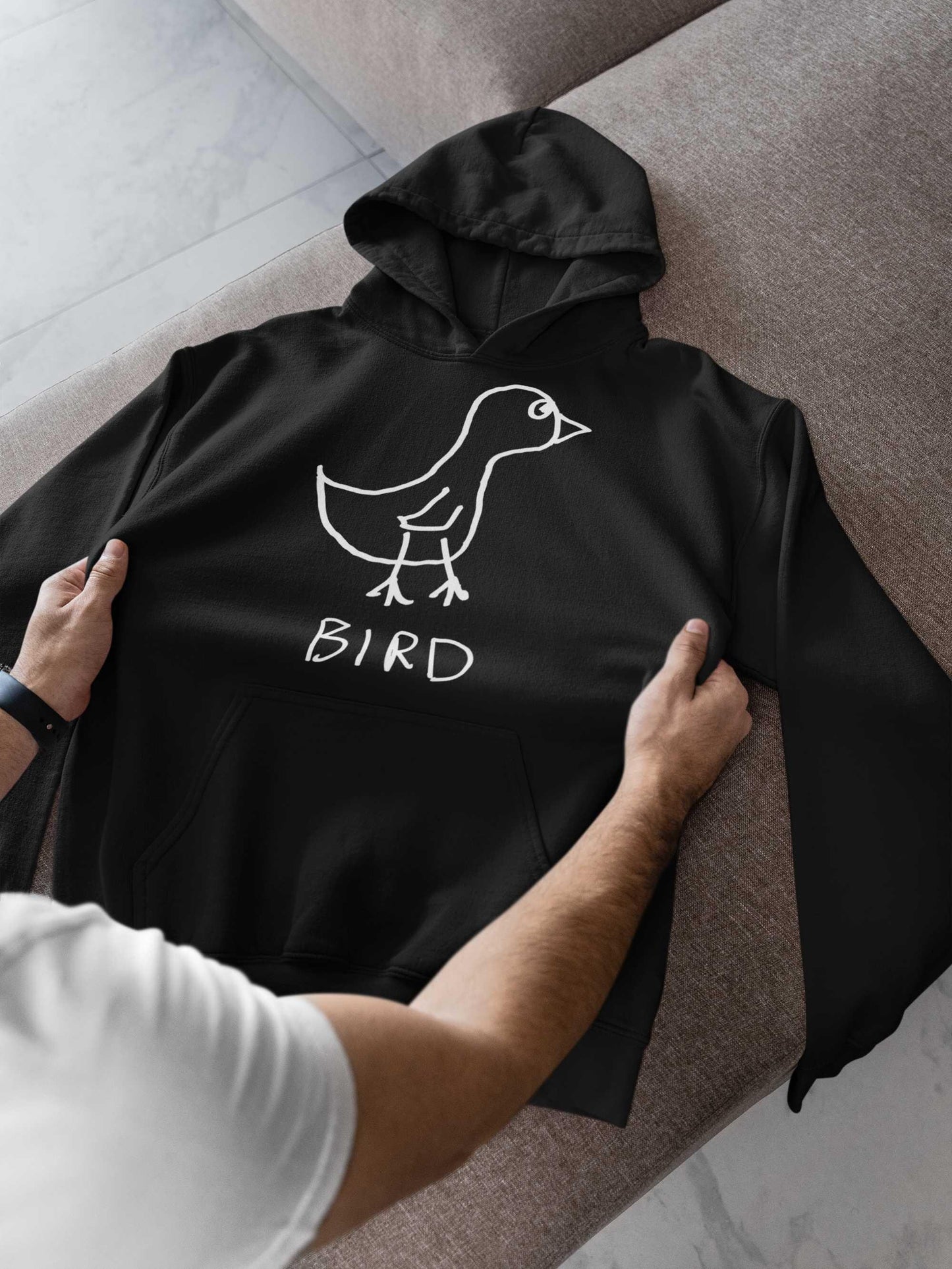 man checking out a new black hooded pullover sweatshirt. featuring a crude marker drawing of a bird with the word "Bird" underneath