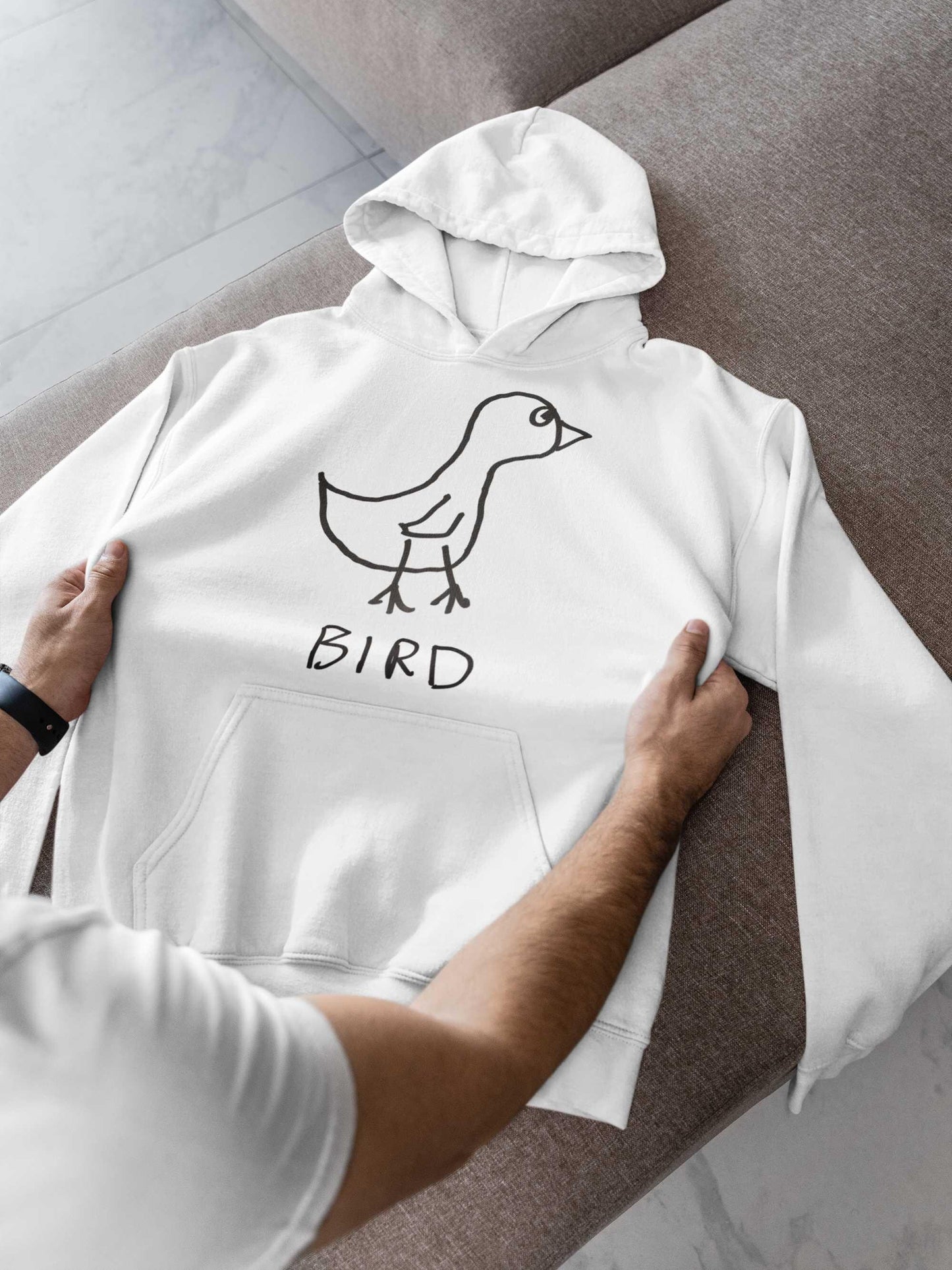 man checking out a new white hooded pullover sweatshirt. featuring a crude marker drawing of a bird with the word "Bird" underneath