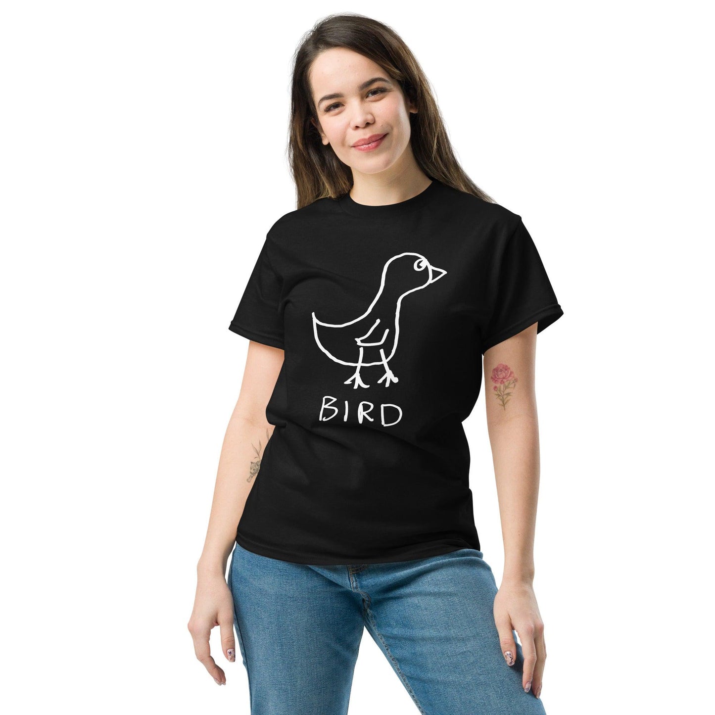 A smiling woman wearing jeans and a black t-shirt featuring a crude marker drawing of a bird with the word "Bird" underneath