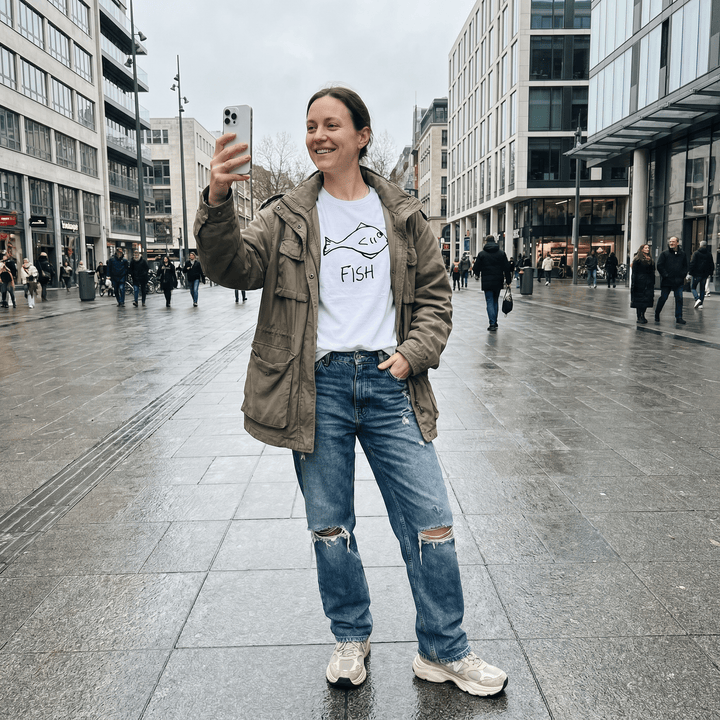 Woman taking a selfie on a city plaza wearing a lo-fi Fish Women&