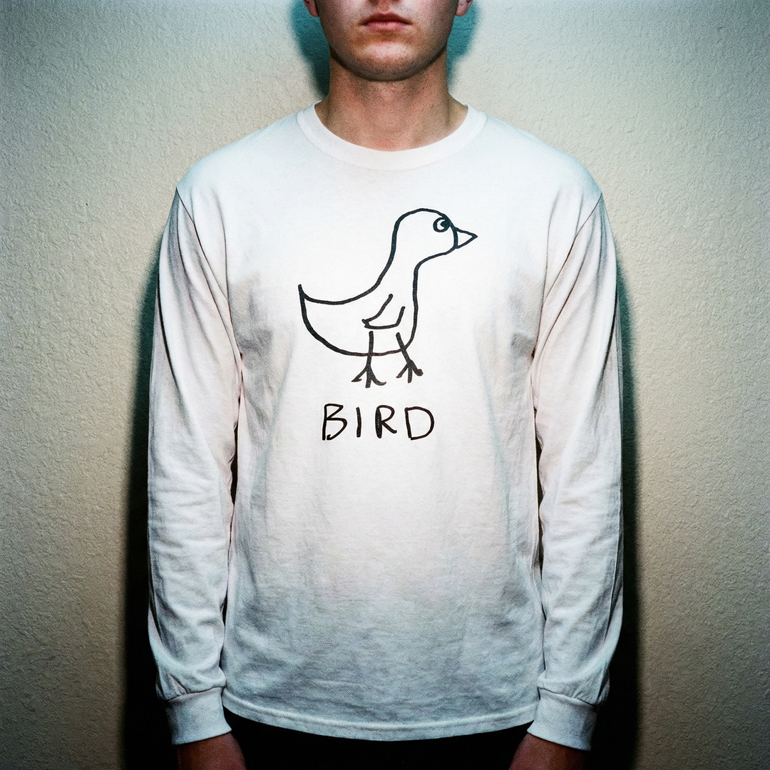 Model wearing a bird long sleeve tee against a pale seamless studio background