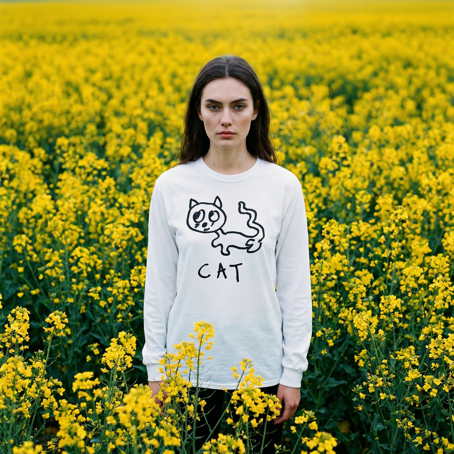 Model in a cat long sleeve tee standing still among tall yellow flowers