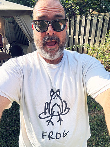 Man wearing a white t-shirt with a LO-FI hand-drawn frog graphic and 'FROG' text, outdoors.