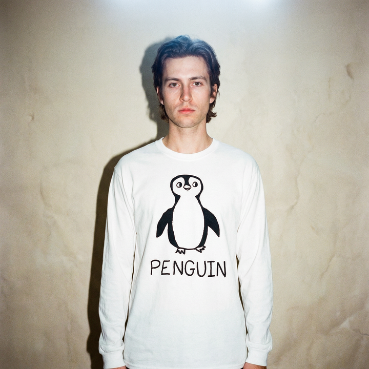 Model in a penguin long sleeve tee standing upright against a stark white backdrop