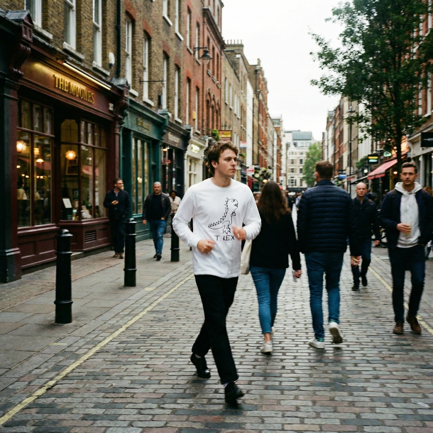 Person in a T-Rex graphic long sleeve stomping through a busy Soho street, London