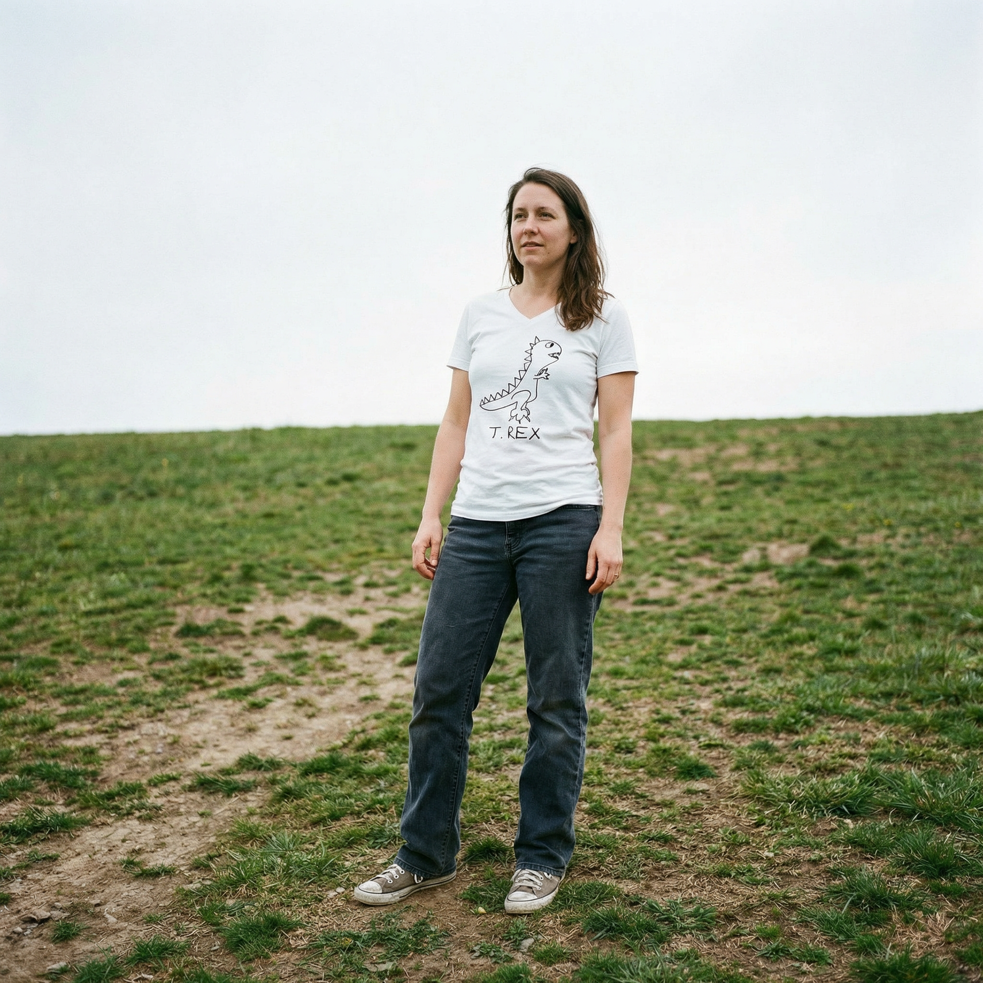 Model in T-Rex v-neck tee in a big open grassy field, arms at sides