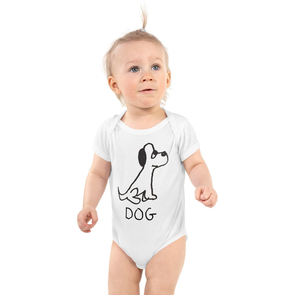 Cute baby standing wearing a white baby onesie featuring a crude marker black and white marker drawing of a cute dog with the word "DOG" handwritten underneath