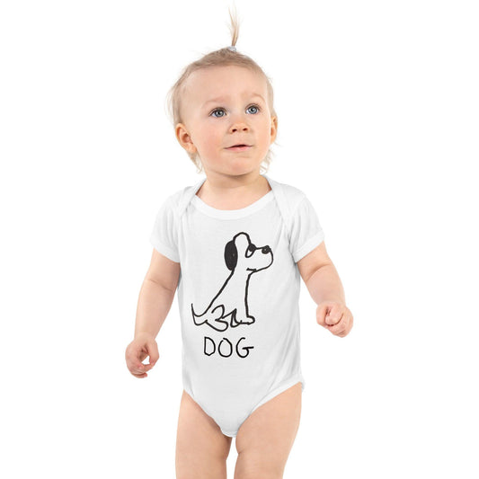 Cute baby standing wearing a white baby onesie featuring a crude marker black and white marker drawing of a cute dog with the word "DOG" handwritten underneath