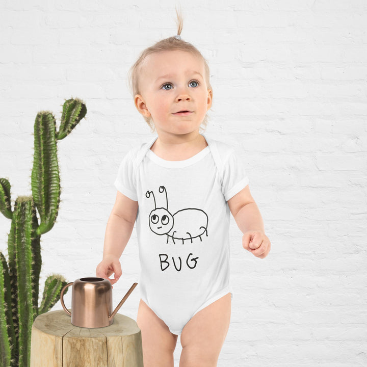 Baby wearing a white onesie with a caterpillar design and the word &