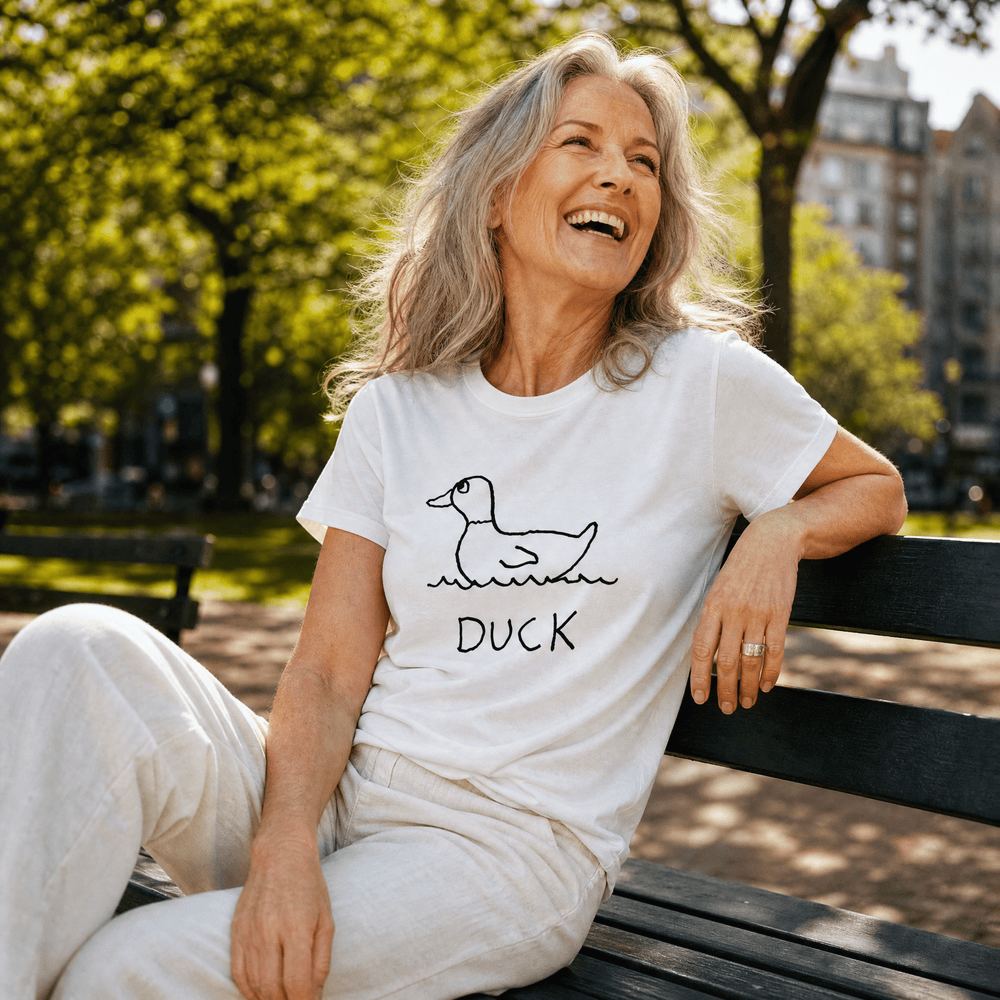 Woman seated on a park bench in a lo-fi Duck Women's Relaxed T-Shirt in white
