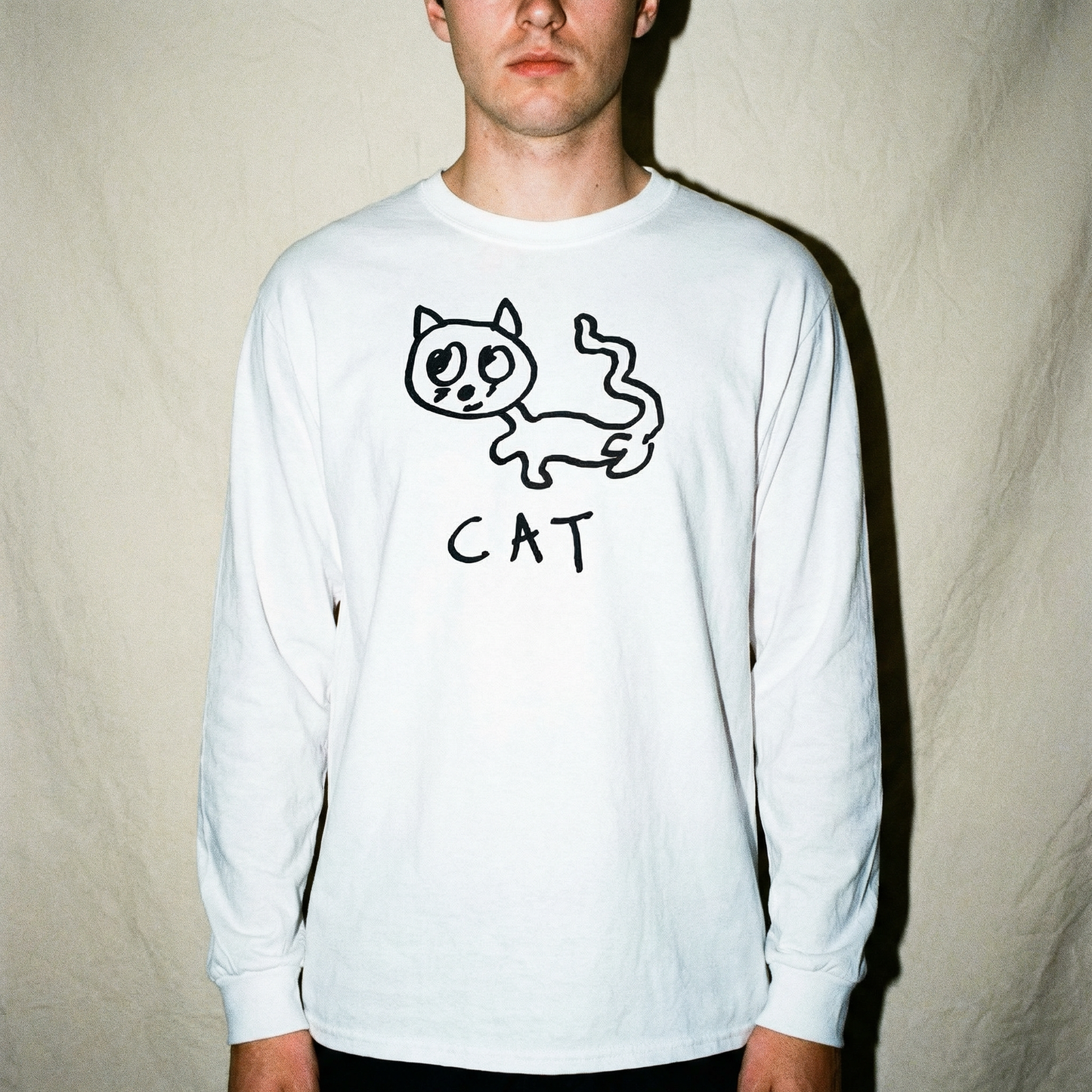 Model in a cat long sleeve tee photographed against a cool grey studio backdrop