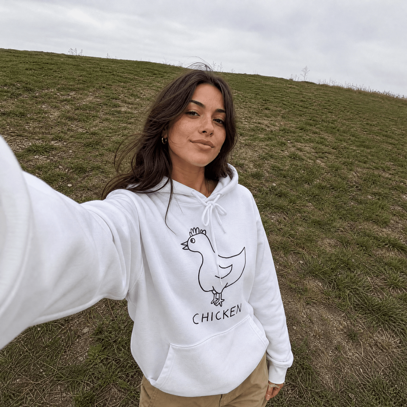 Woman on a grassy field wearing a lo-fi Chicken Hoodie