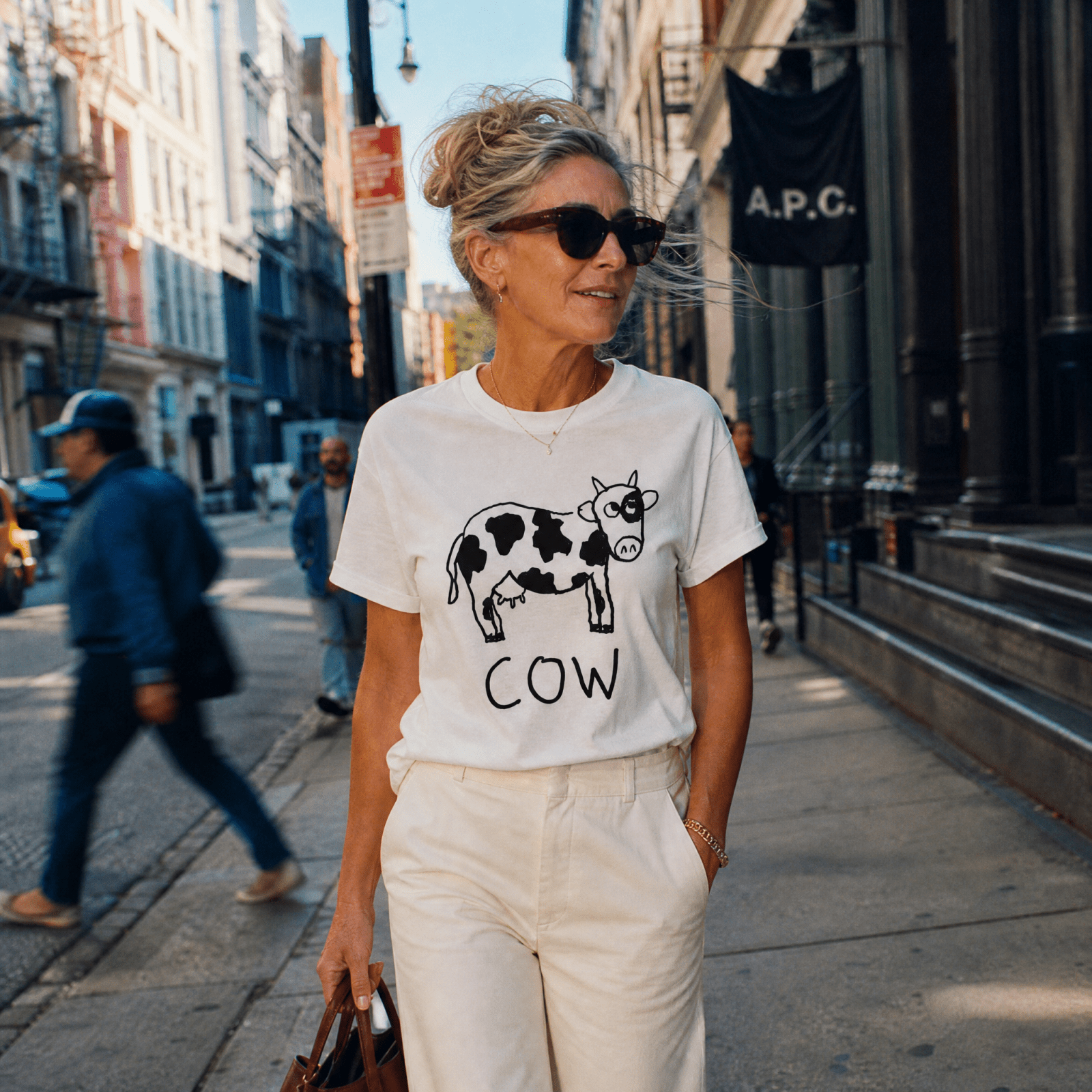 Woman with sunglasses walking down a Soho street wearing a lo-fi Cow Classic Tee