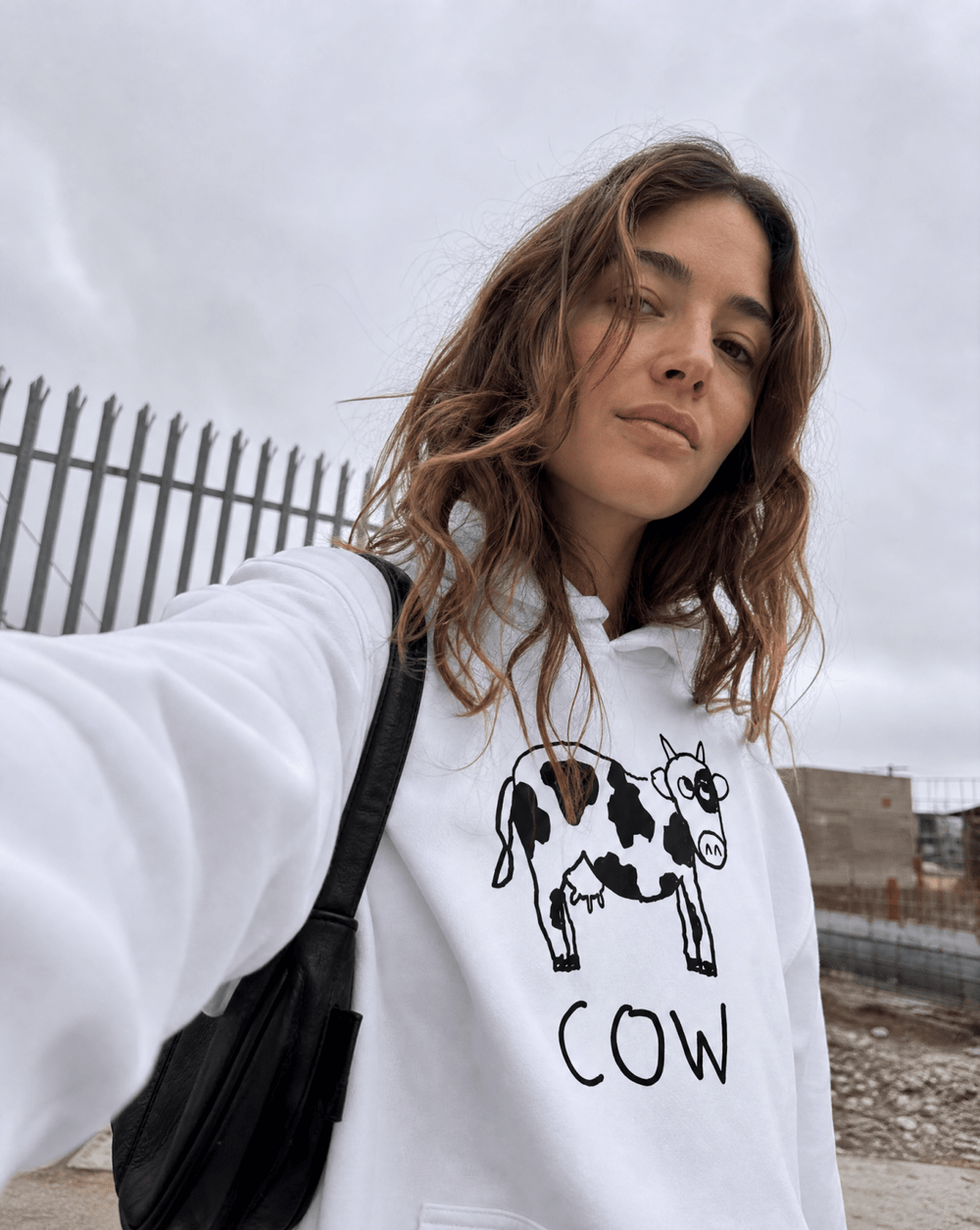 Woman taking a selfie wearing a lo-fi Cow Hoodie