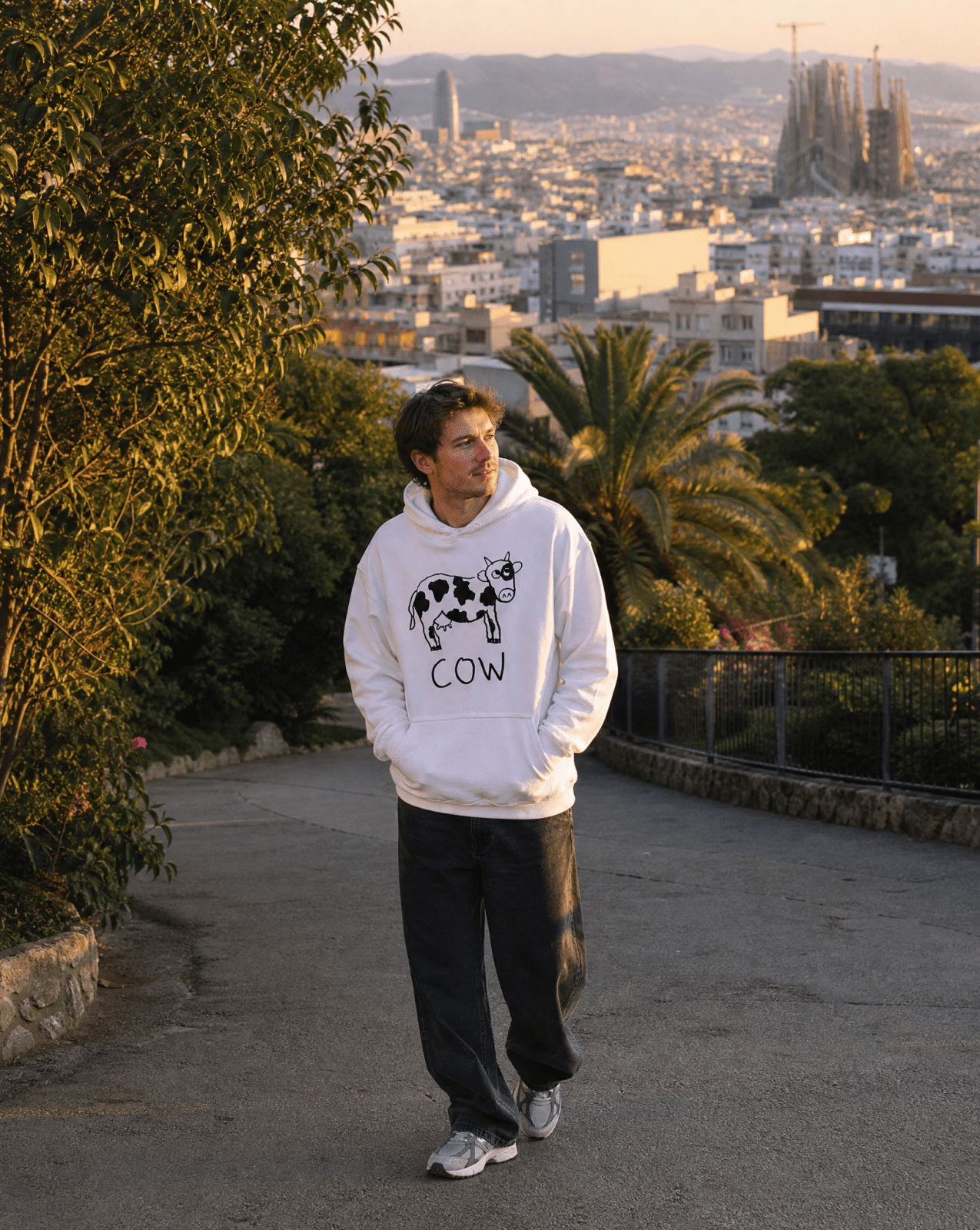 Man walking through Barcelona hills wearing a lo-fi Cow Hoodie