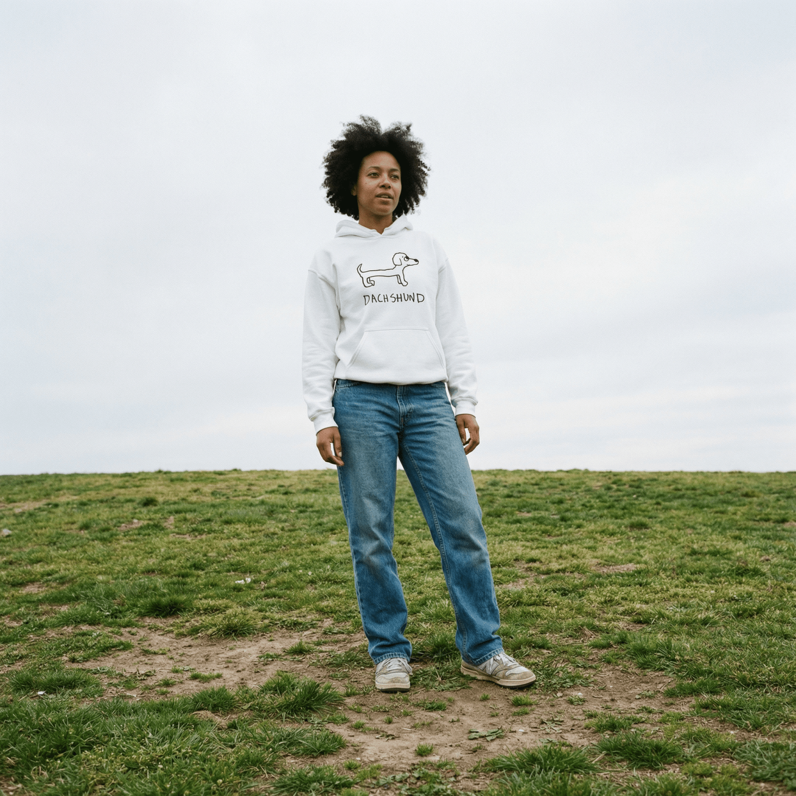 Woman standing on a grassy hill wearing a lo-fi Dachshund Hoodie