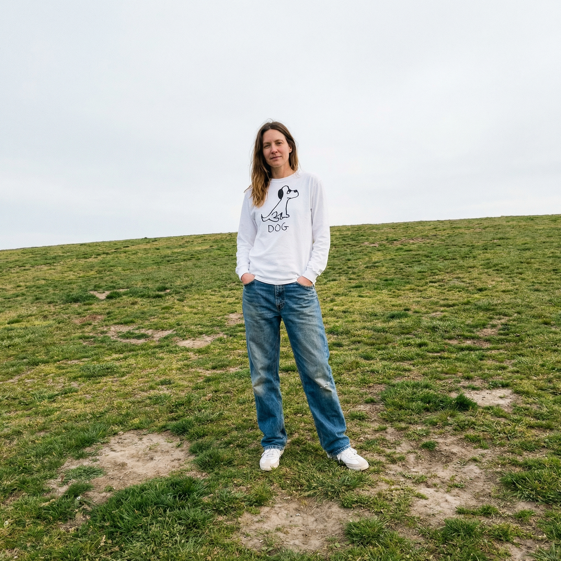 Model wearing a dog long sleeve tee relaxed in a wide open grassy field