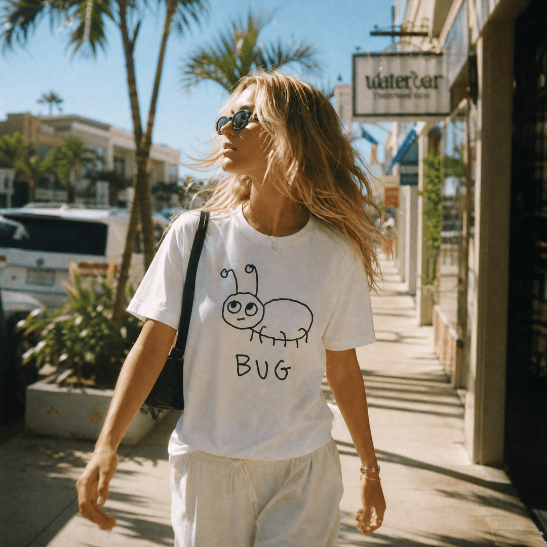 Woman walking a palm-lined beach town street in a lo-fi Bug Women&
