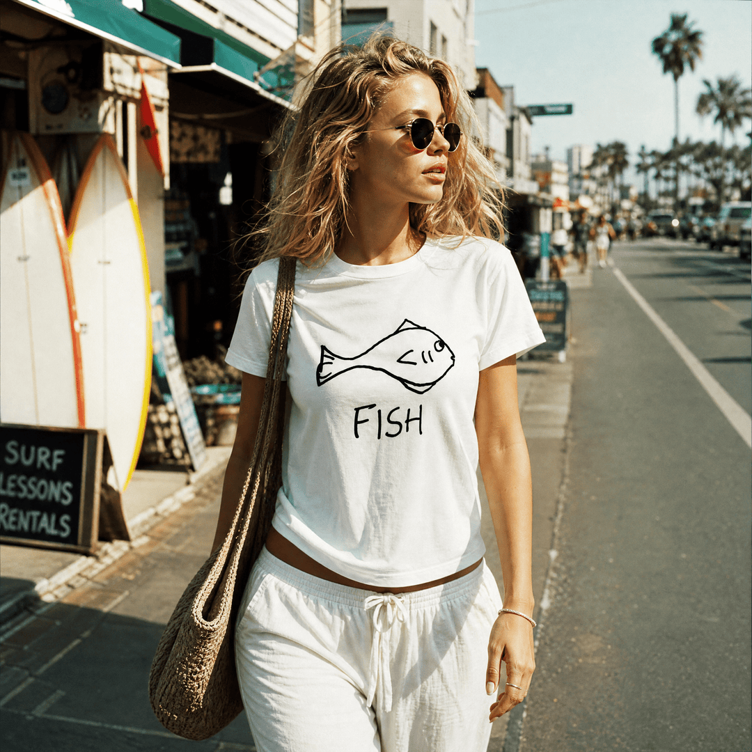 Woman with a shoulder bag walking a beach town street wearing a lo-fi Fish Women&