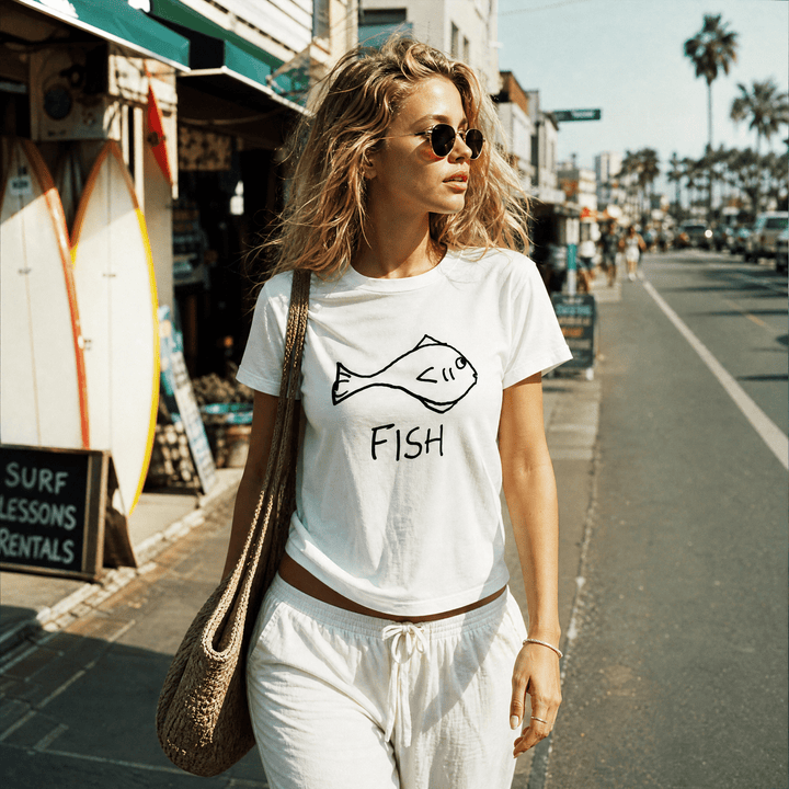 Woman with a shoulder bag walking a beach town street wearing a lo-fi Fish Women&