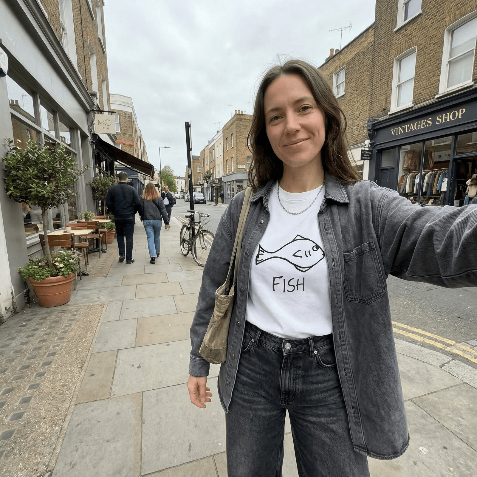 Woman taking a selfie on a city street wearing a lo-fi Fish Classic Tee