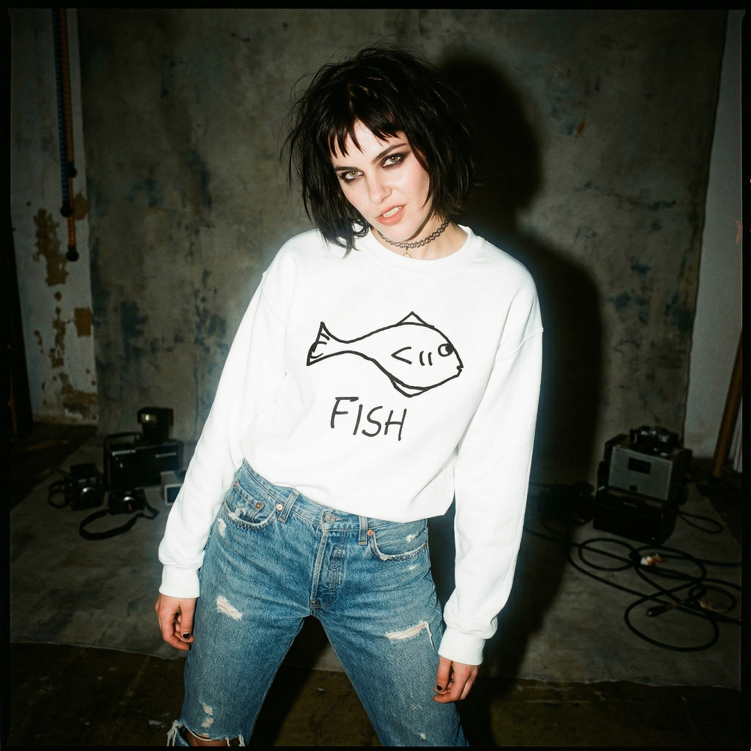 90s grunge style Person wearing a white sweatshirt with a fish graphic and text, standing in a room with a textured wall.