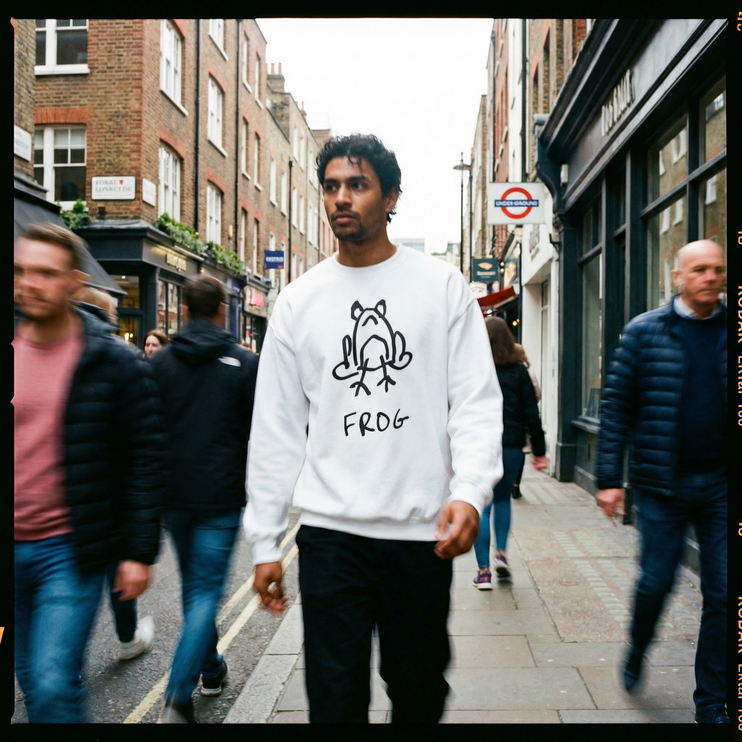 Person in a frog sweatshirt on a rainy Soho street, puddles reflecting the lamplight