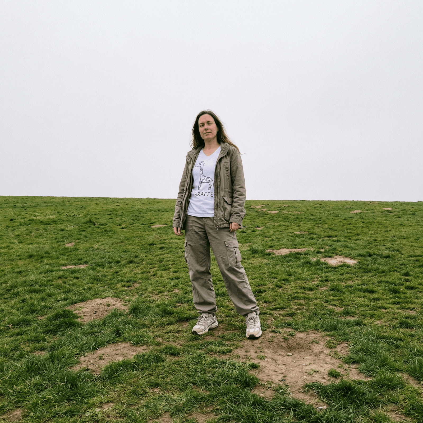 Woman standing on a grassy field wearing a lo-fi Giraffe V-Neck T-Shirt in white