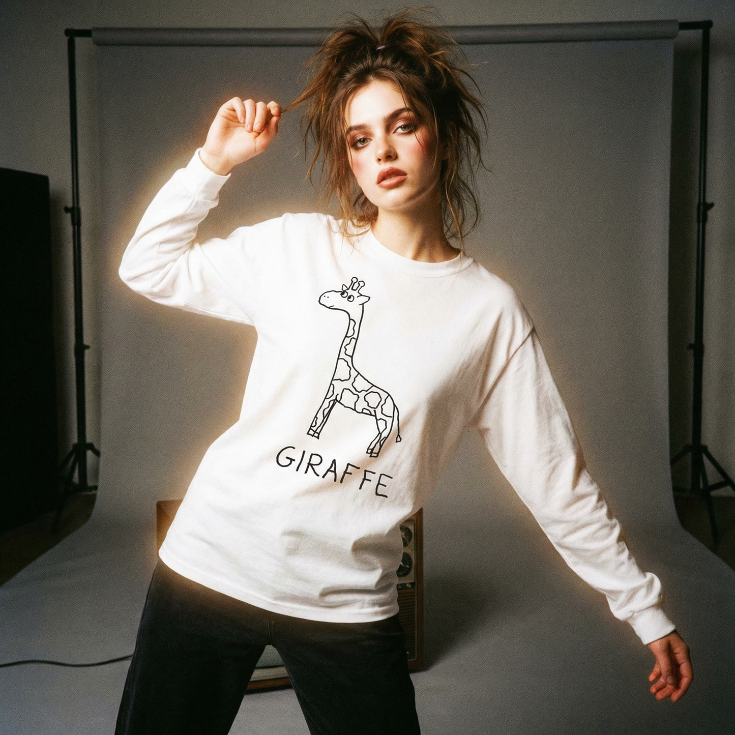 Person wearing a white sweatshirt with a hand drawn giraffe design and 'GIRAFFE' text in a 90's studio setting.