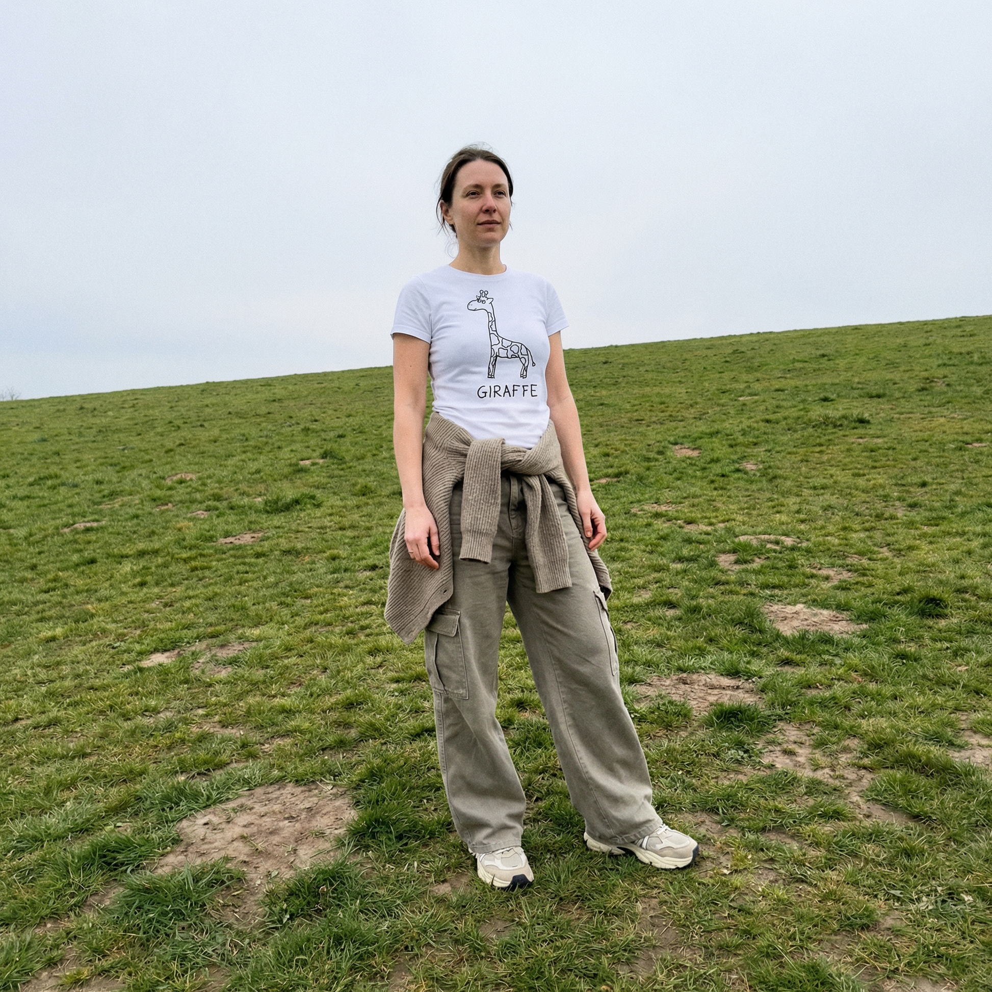 Giraffe women's tee worn outdoors – minimalist lofi giraffe shirt in grassy field