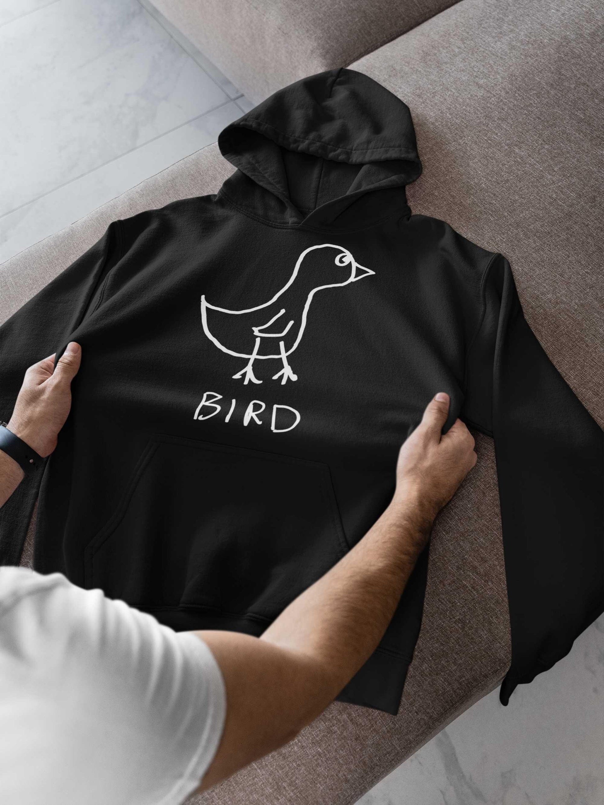 man checking out a new black hooded pullover sweatshirt. featuring a crude marker drawing of a bird with the word "Bird" underneath