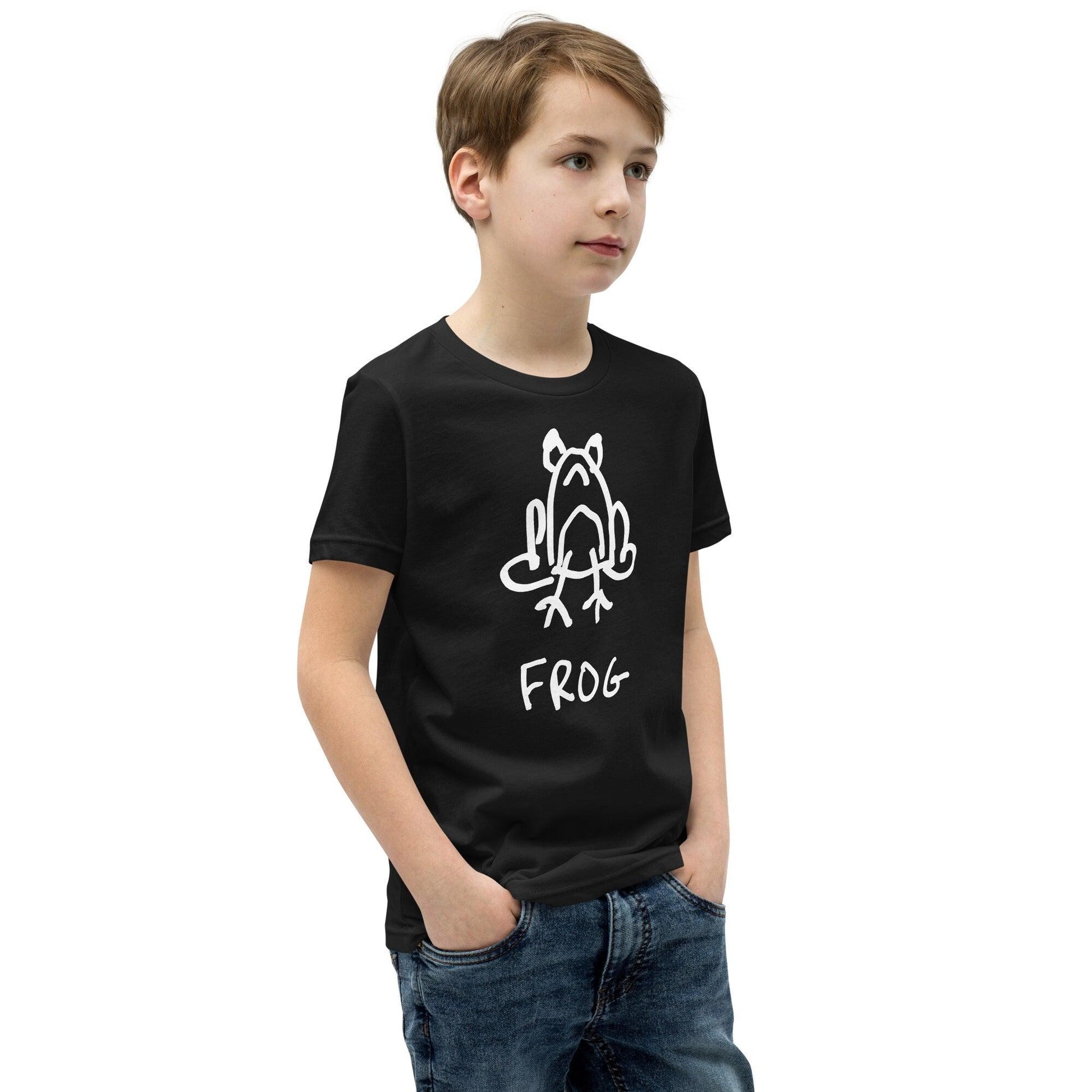 Young boy wearing a kid's black t-shirt featuring a crude but cute black and white marker marker drawing of a cute frog with the word “FROG” handwritten underneath