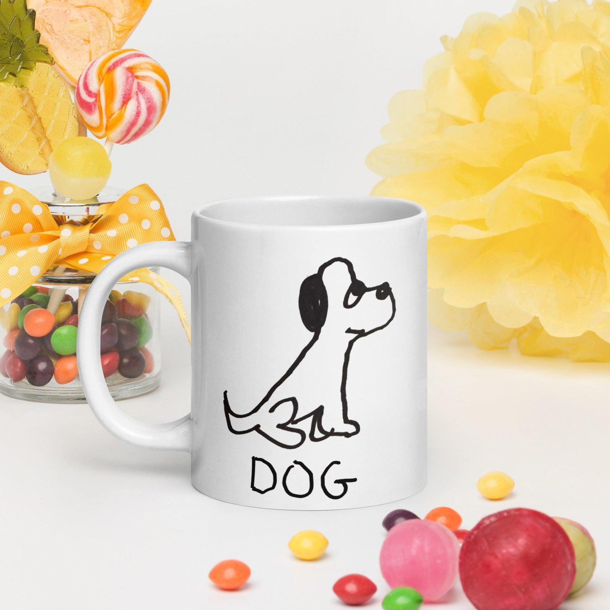 white coffee mug  featuring a crude marker black and white marker drawing of a cute dog with the word "DOG" handwritten underneath, surrounded by candy 