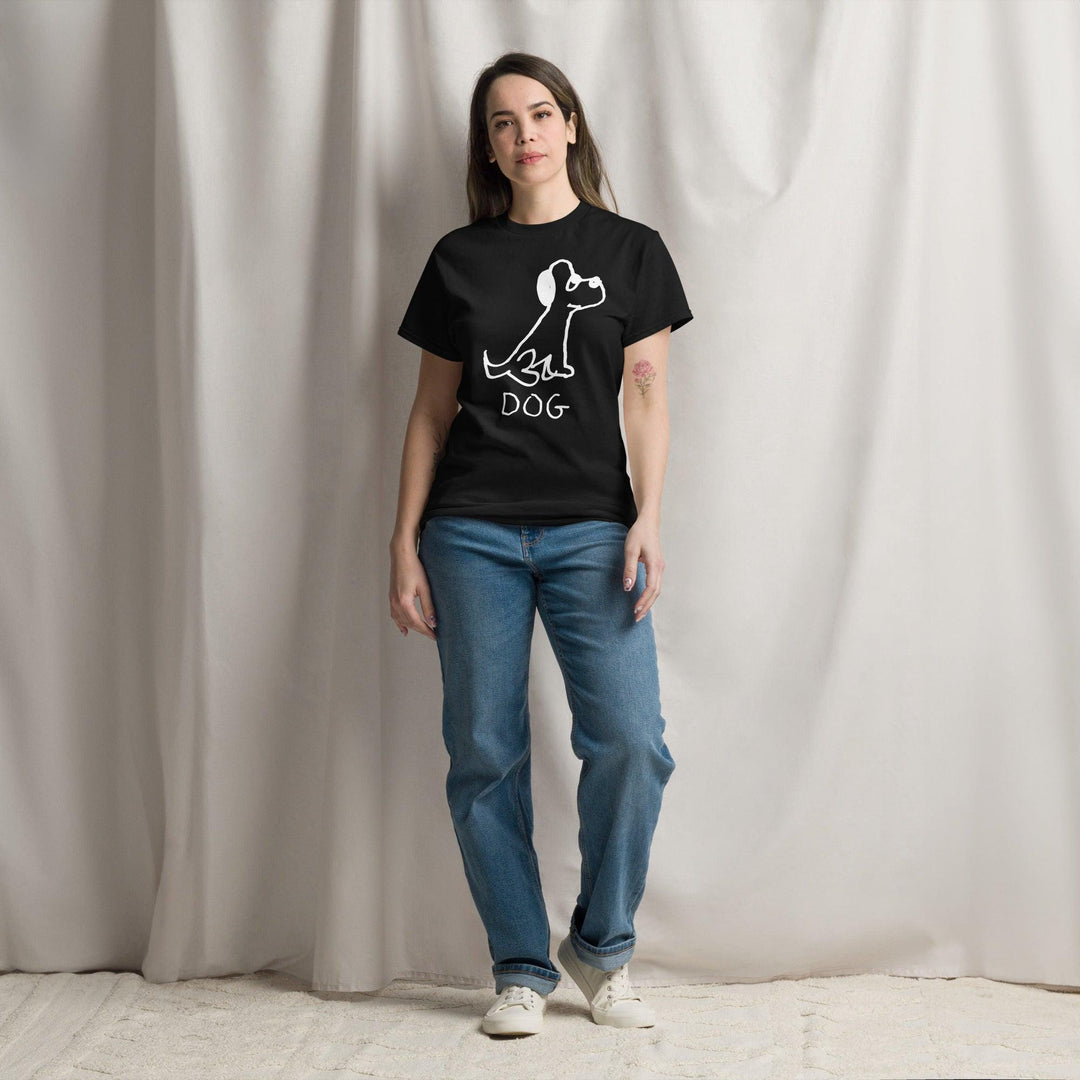 Pretty young woman standing against a white curtain background, wearing jeans and a black classic t-shirt  featuring a crude marker black and white marker drawing of a cute dog with the word "DOG" handwritten underneath