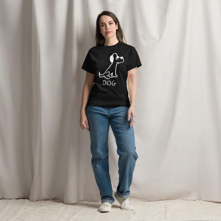Pretty young woman standing against a white curtain background, wearing jeans and a black classic t-shirt  featuring a crude marker black and white marker drawing of a cute dog with the word "DOG" handwritten underneath