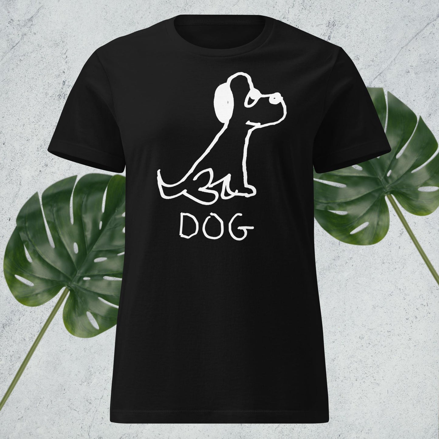 mockup of black women's fitted t-shirt featuring a crude marker drawing of a dog with the word "DOG" handwritten underneath, against a gray background with green leaves. 