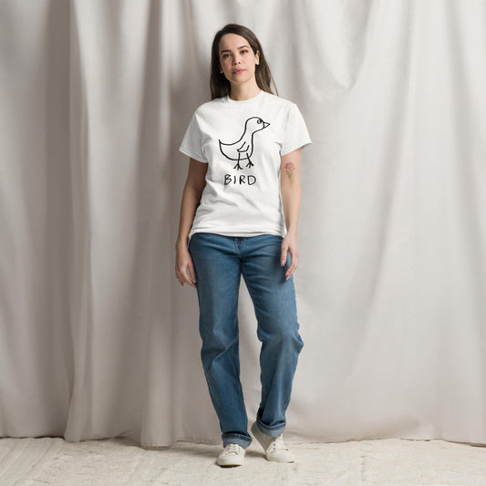 a hip young woman against a white curtain wearing a white t shirt featuring a crude marker drawing of a bird with the word "Bird" underneath