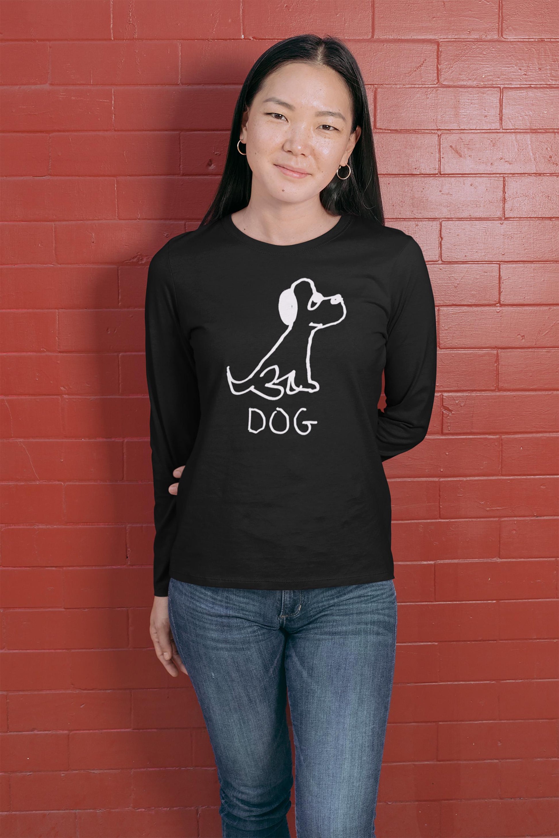 cool young woman wearing a black long-sleeve shirt White Long sleeve tee featuring a crude marker black and white marker drawing of a cute dog with the word "DOG" handwritten underneath on a polka dot background.  against a red brick wall.