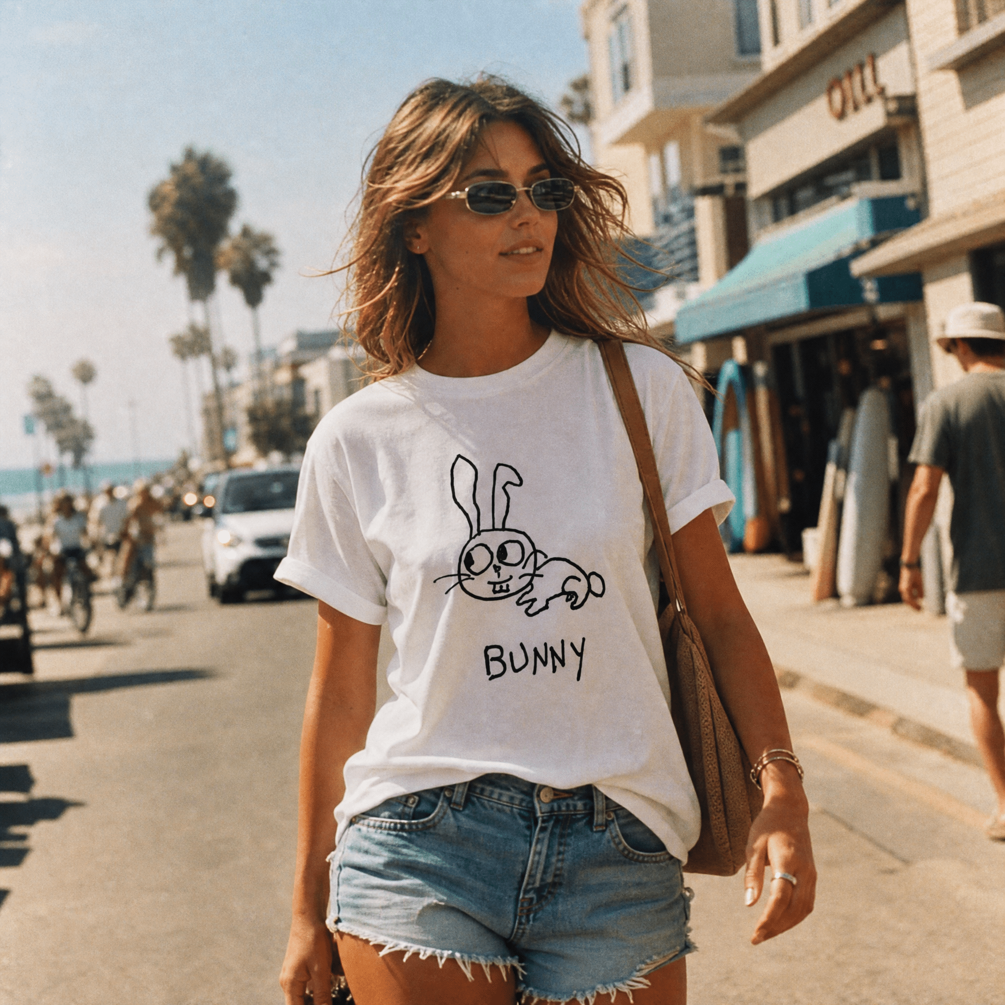 Woman walking a palm-lined beach town street in a lo-fi Bunny Women's Relaxed T-Shirt in white
