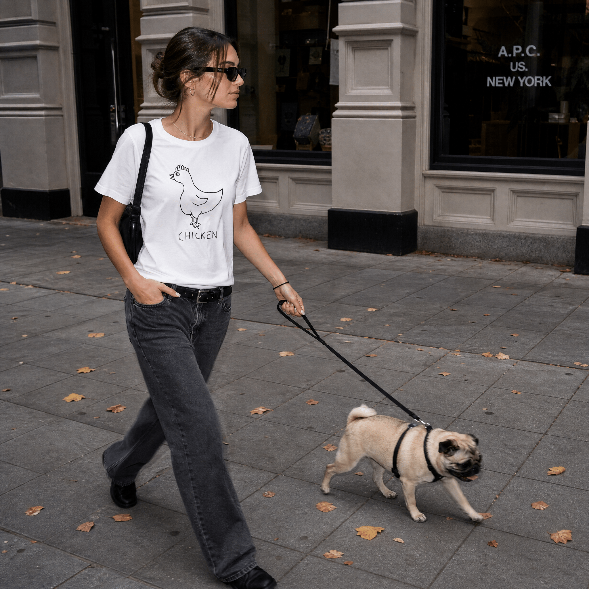 Woman walking a dog on a city street in a lo-fi Chicken Women's Relaxed T-Shirt in white