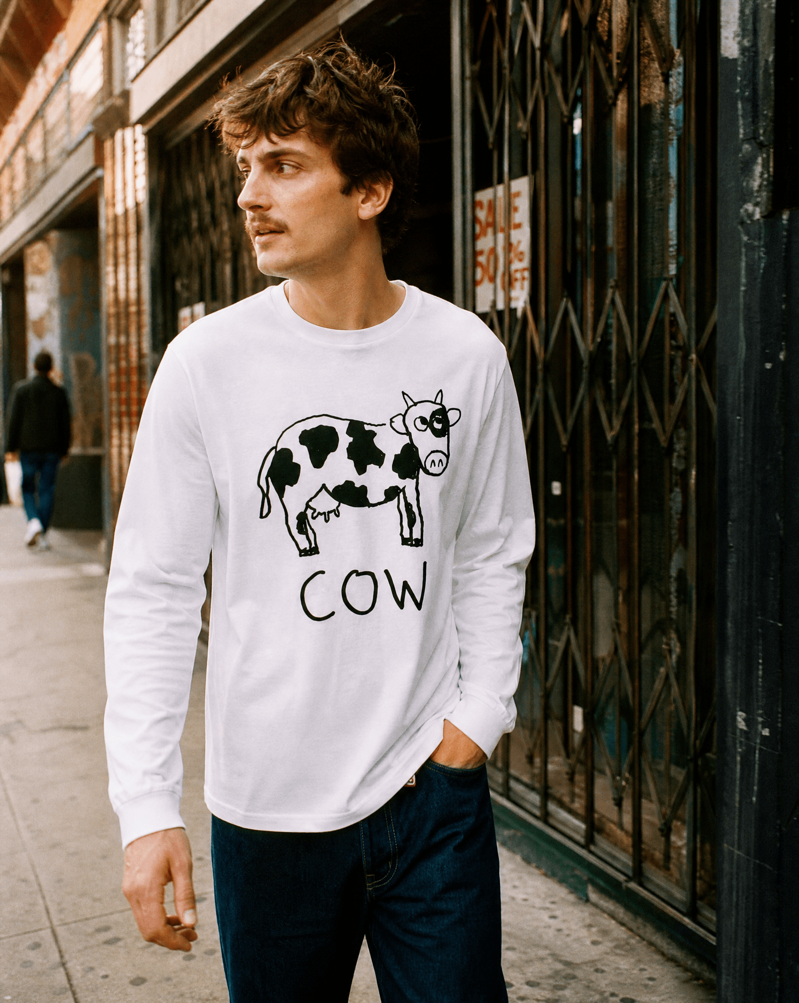 Woman walking a SoHo shopping street in a lo-fi Cow Long Sleeve Tee in white