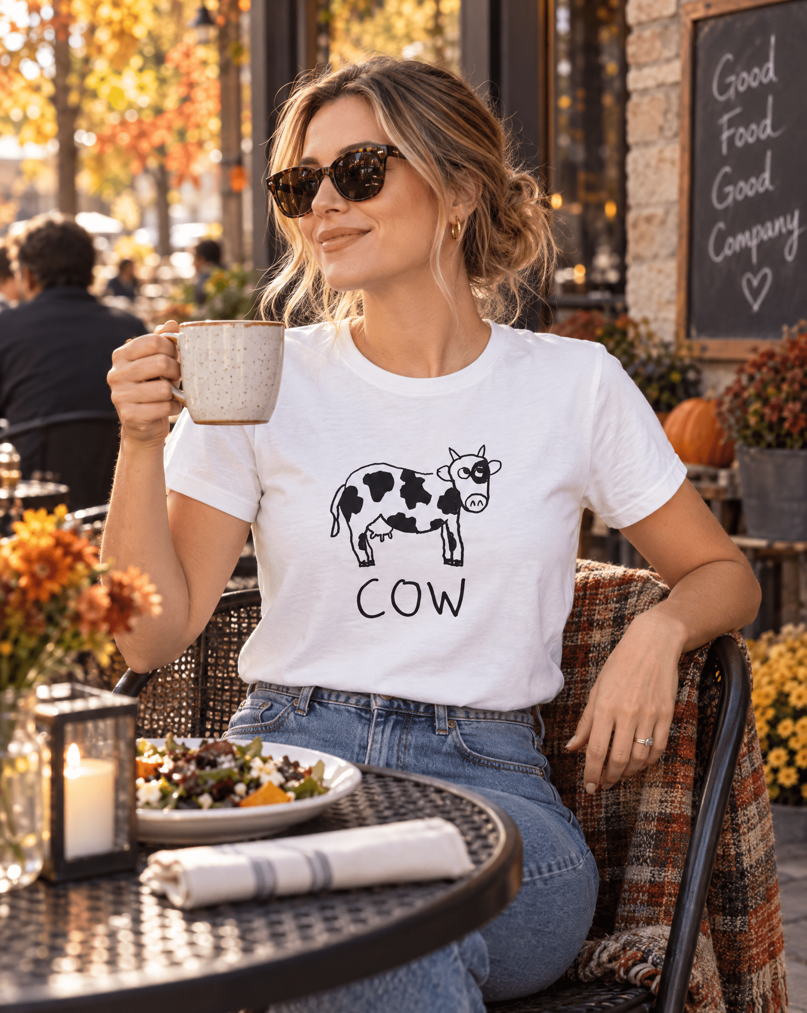 Sep 29 cow women's tee — autumn patio lifestyle photo