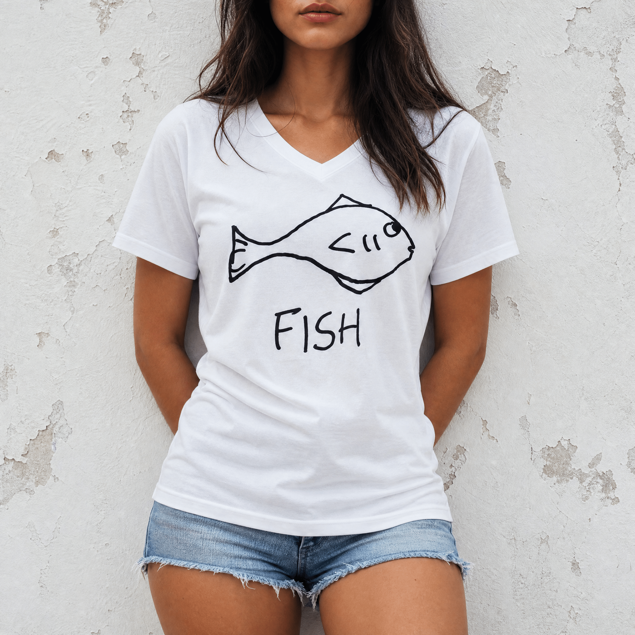 Woman standing against a white plaster wall wearing a lo-fi Fish Women's V-Neck Tee