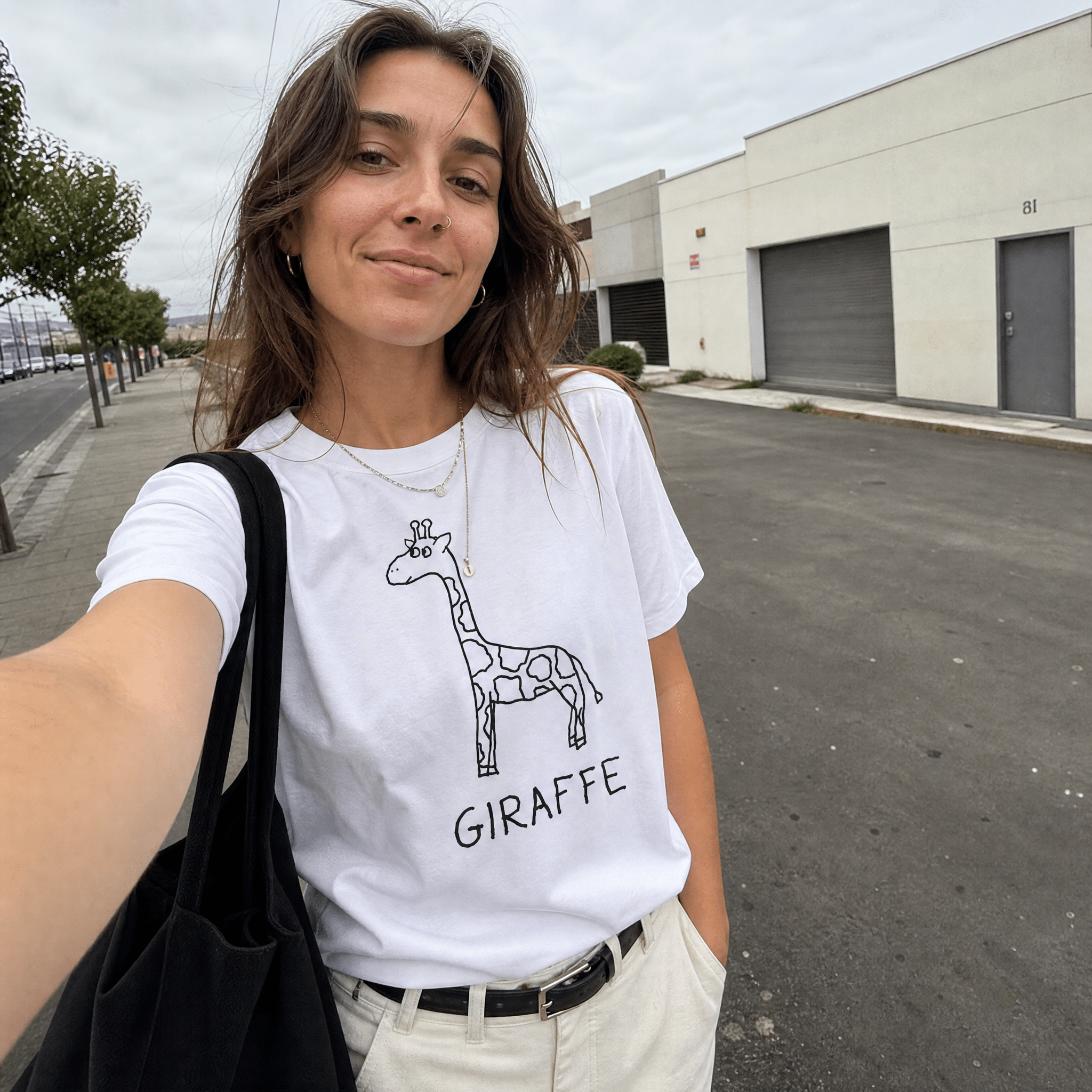 Woman taking a selfie on an urban street wearing a lo-fi Giraffe Women's Relaxed T-Shirt in white
