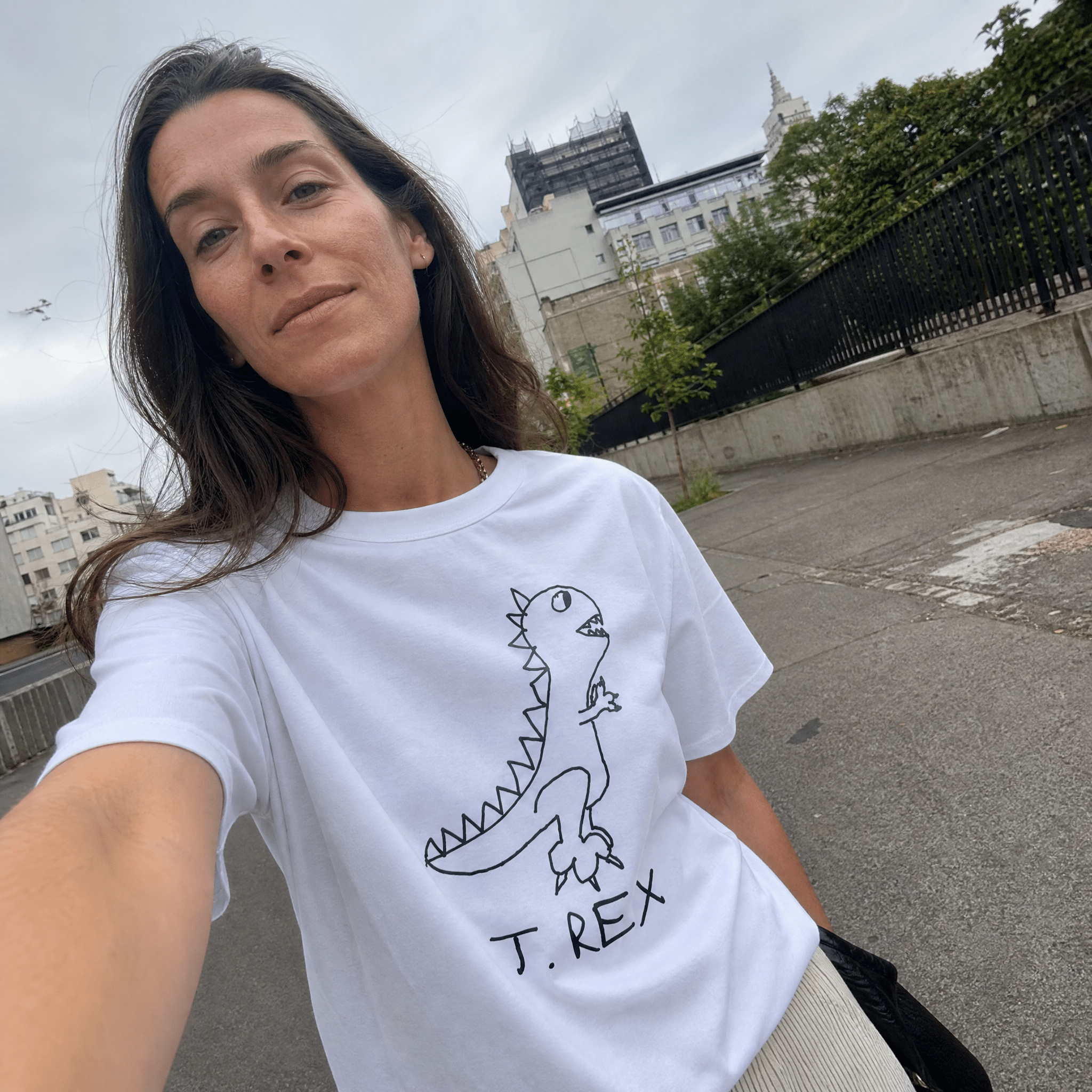 Woman taking a street selfie in a lo-fi T. Rex Women's Relaxed T-Shirt in white