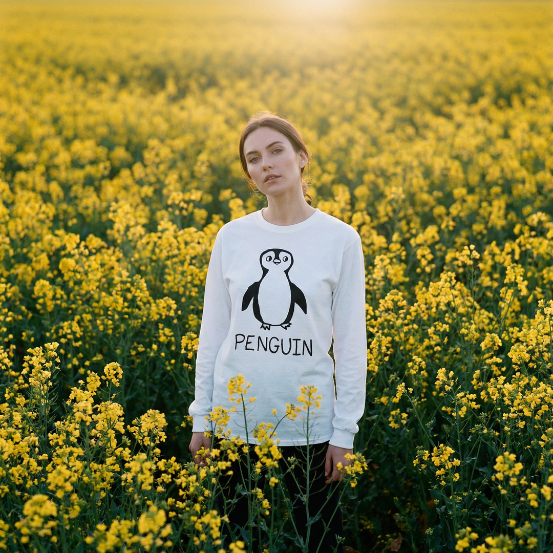 Model wearing a penguin long sleeve tee in a cheerful field of yellow flowers