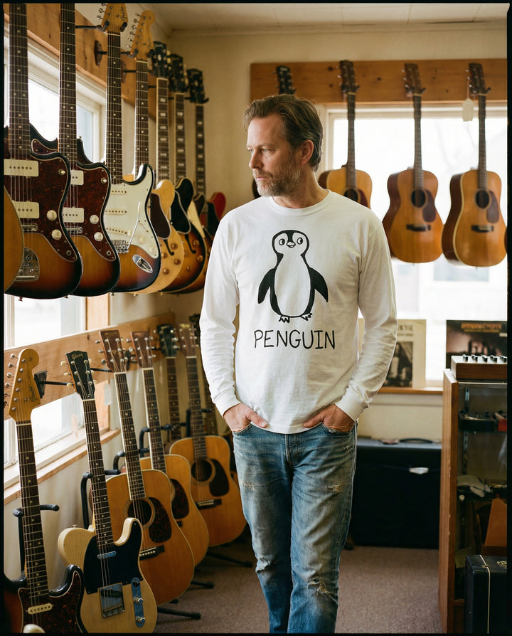 Person in a penguin graphic long sleeve tee shopping in a guitar shop.