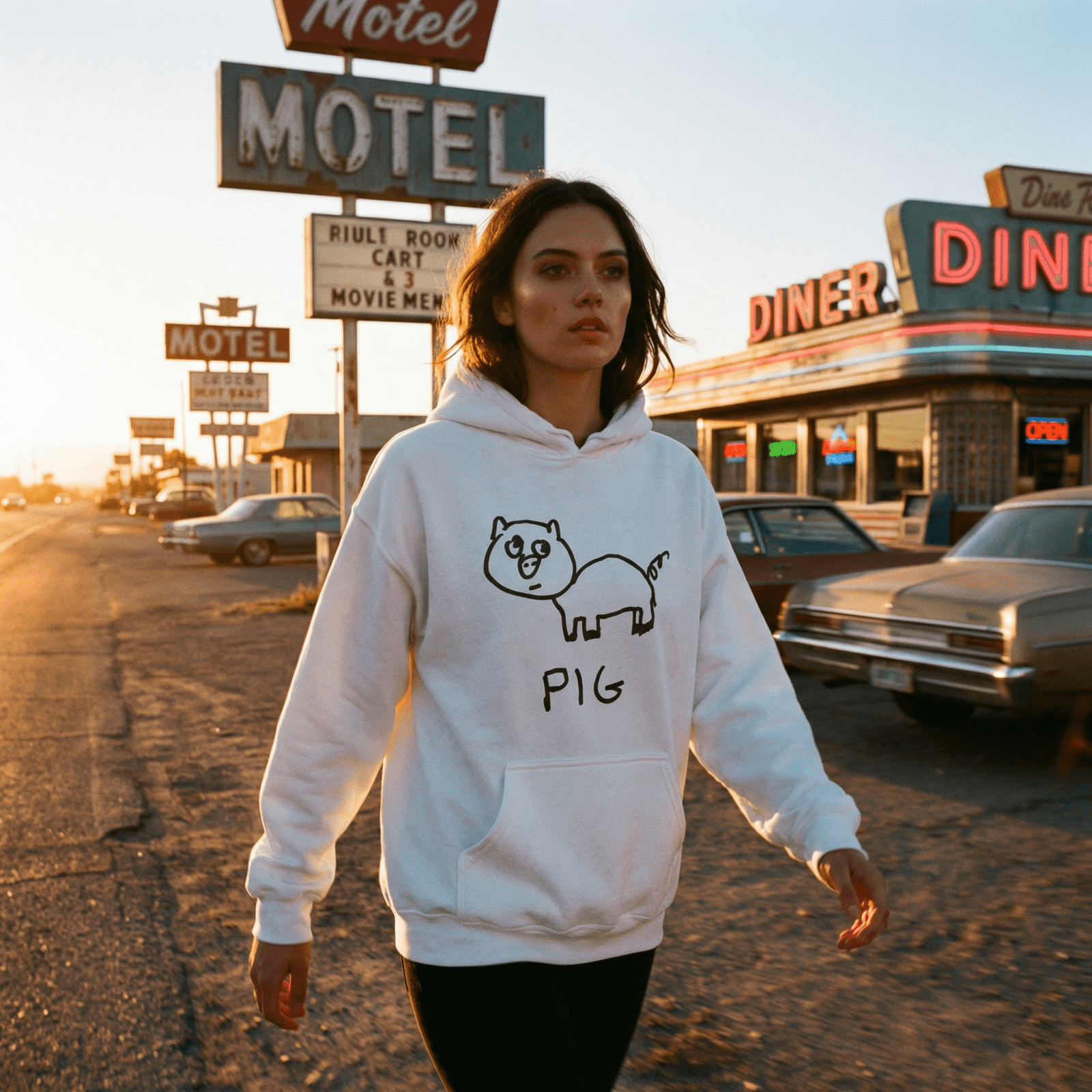 Woman walking past a desert motel diner at sunset wearing a lo-fi Pig Hoodie in white