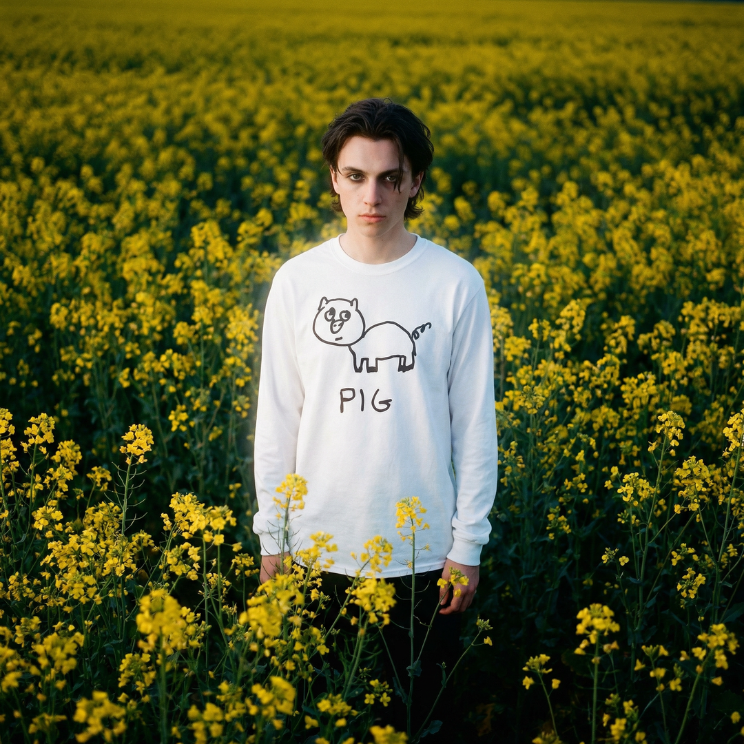 Model in a pig long sleeve tee grinning in a sunny field of yellow flowers